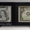 Close front view of two black carbon-fiber 4-mil currency display frames with sample U.S. banknotes